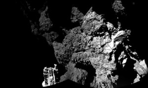 The fiorst image sent back by Philae from the surface of the comet. The lander's leg is in the bottom right corner.