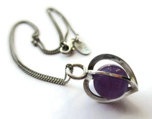 Caged amethyst bead ina heart-shaped sterling silver cage, by Elis Kauppi for Kupittaan Kulta.